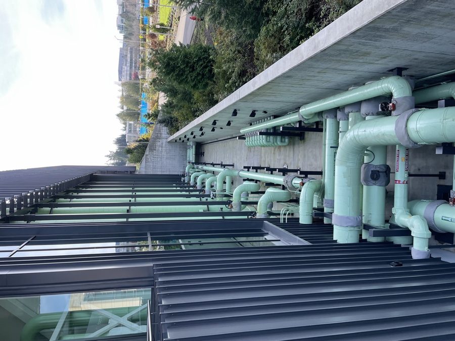 Pale-green thermal pipes running along the outside of the Thermal Energy Center